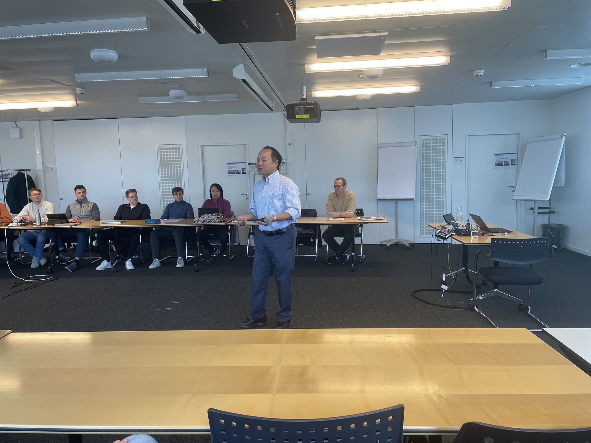Chris Tang standing in the room with students in the background