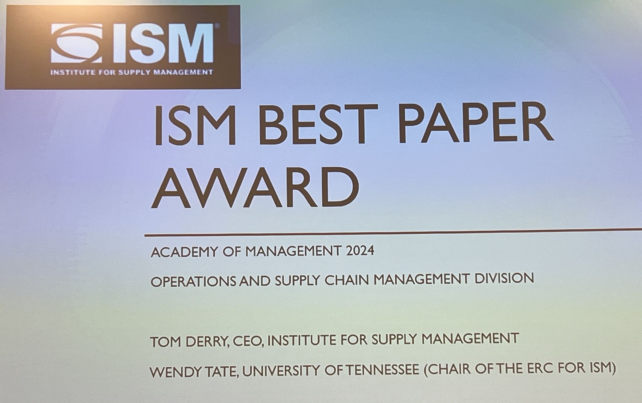 a projected presentation slide reading "ISM Best Paper Award"