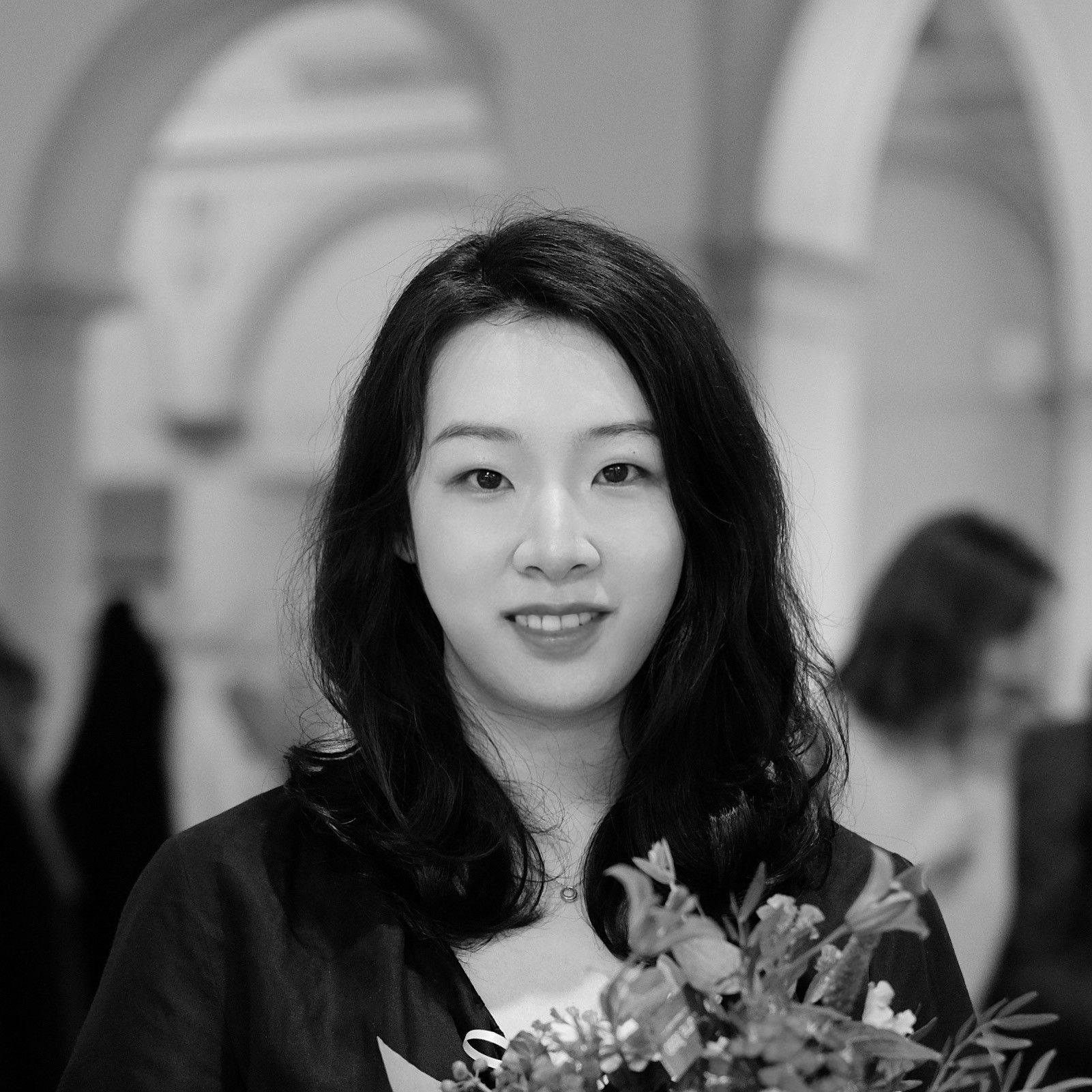Headshot of Yan Zou holding a bouquet of flowers in black and white